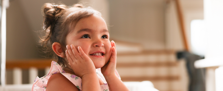 toddler with hands on her face smiling